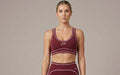 Women's maroon sports bra with light pink contrast trim and fine stitching details, featuring a supportive elastic hem and precise Double Take Topstitching.