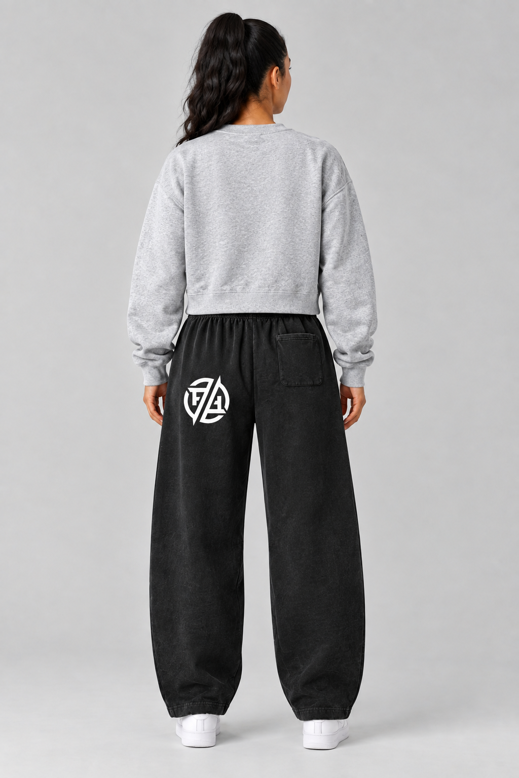 Back view of model wearing gray sweatshirt and black barrel-leg pants