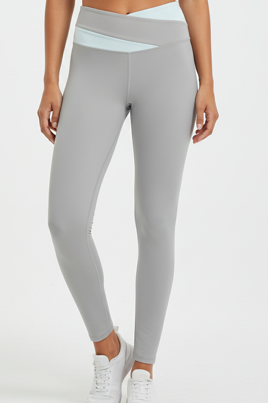 Fitness model wearing FyneFIT light gray and light blue color block yoga leggings on a plain studio background